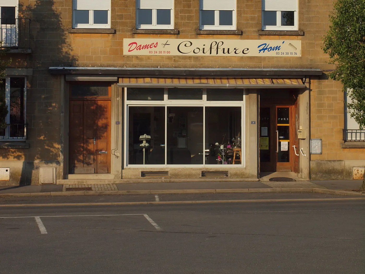 La façade d'un salon de coiffure de village avec son enseigne Dames et Hommes