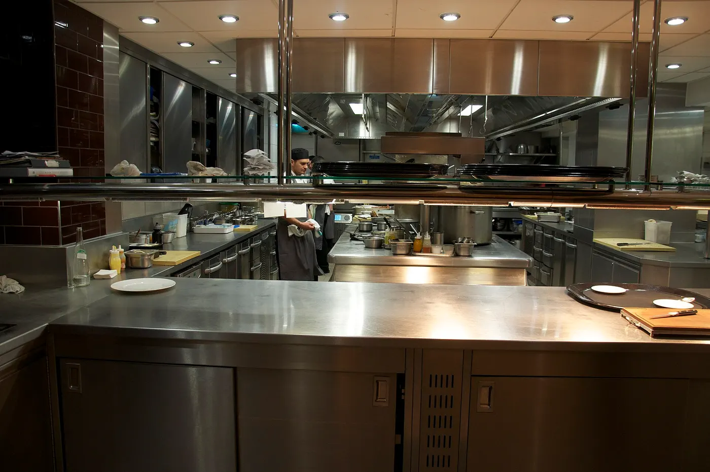 Une cuisine professionnelle en inox avec un cuisinier au fond