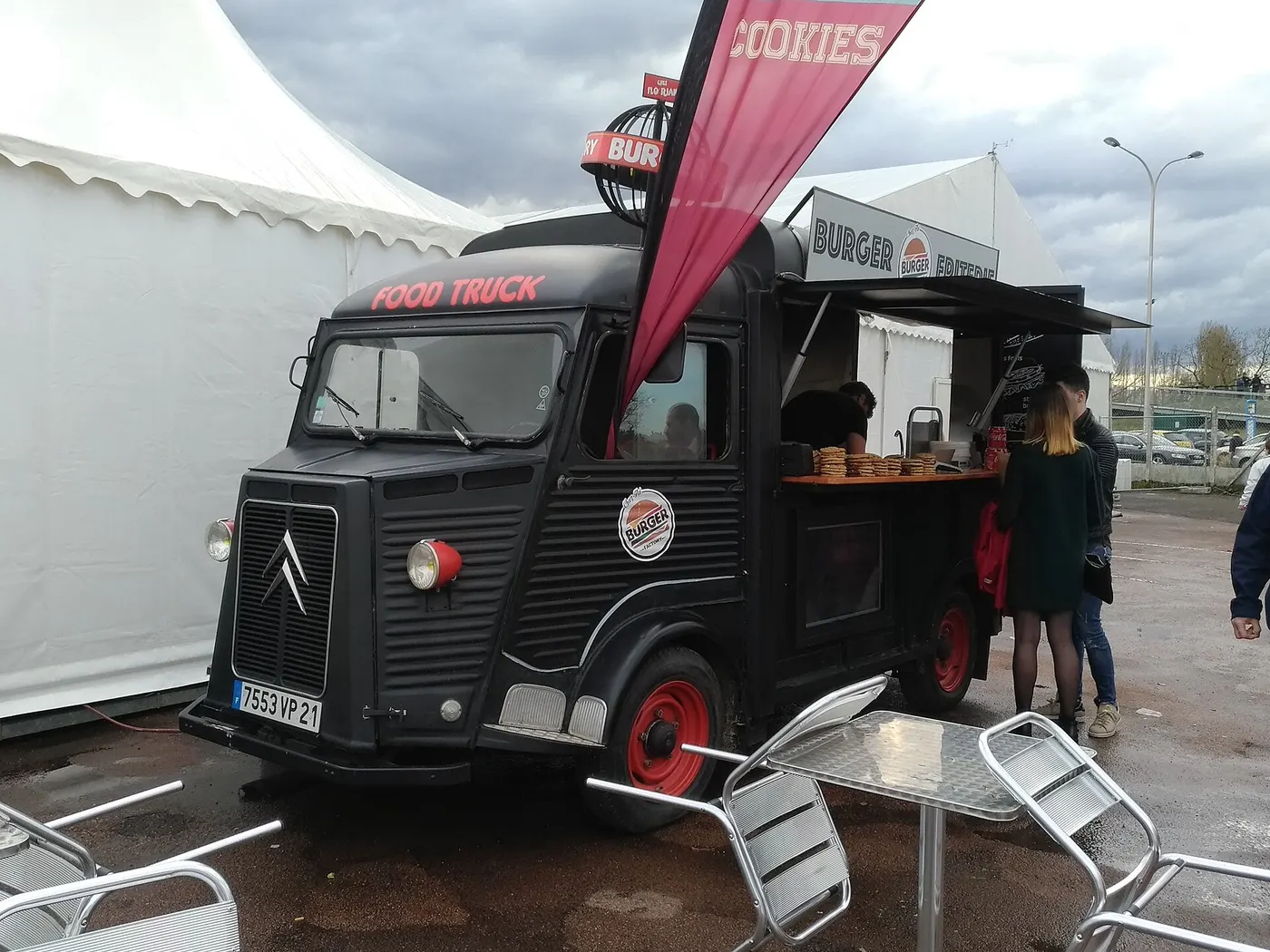 Un food truck noir sur base de Citroën Type H, des clients au comptoir